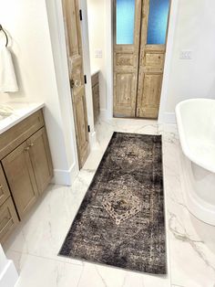 a bath room with a tub and a rug on the floor in front of it