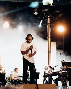 a man standing on top of a stage holding a microphone in front of other people