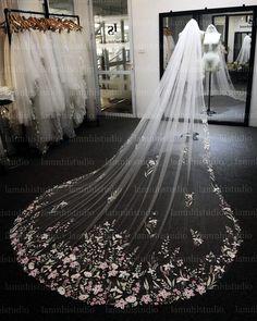 a wedding veil with pink flowers on it in front of a store display window and mannequins