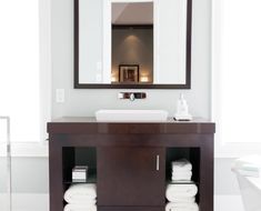 a bathroom with a sink, mirror and towels on the shelf in front of it