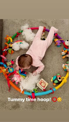 a baby is laying on the floor surrounded by stuffed animals and toys, with a caption that reads tummy time hop