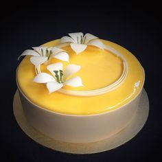 there is a yellow cake with white flowers on the top and bottom, sitting on a plate