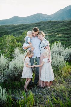 a family standing in the grass with mountains in the background