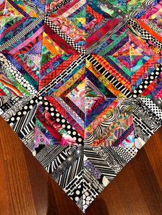 a very colorful quilt on top of a wooden table