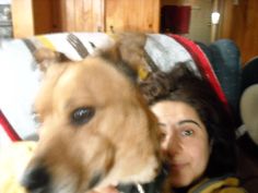 a woman sitting on a couch next to a dog with her head on the pillow