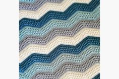 a crocheted afghan is shown with blue and white waves on the side,