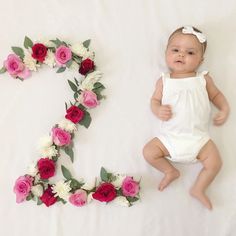 a baby laying next to the letter e with flowers