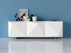 a white sideboard against a blue wall in a room with an art work on it