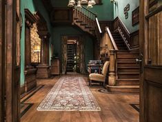 a large wooden staircase leading up to a living room with green walls and wood floors