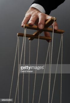 a hand holding an object with strings hanging from it's sides, in front of a gray background