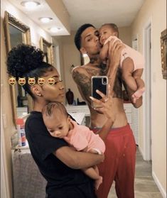 three people are taking a selfie in the mirror with one person holding a baby