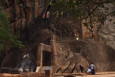 two people are standing on the steps leading up to a rock formation with an elephant statue