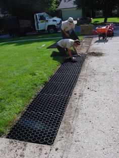 two men working on a drainage system in the grass