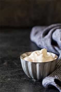 a silver bowl filled with whipped cream on top of a counter next to a gray towel