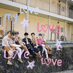 group of young men sitting on top of a stone wall in front of a building