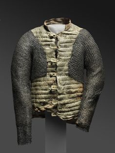 an old jacket that has been worn and covered with metal mesh, on display in a museum