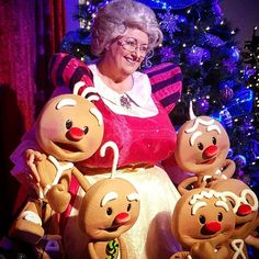 an older woman sitting in front of a christmas tree with her three little reindeer dolls