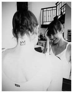 two women with tattoos on their backs are looking at each other in the same direction