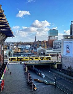 a yellow train traveling over a bridge in the middle of a city with tall buildings