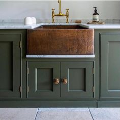 a kitchen sink sitting under a faucet next to green cabinets