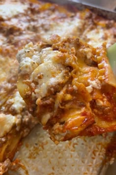 a slice of pizza with cheese and sauce being lifted from the casserole dish