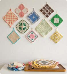 the wall is decorated with colorful crocheted squares and potholders hanging from hooks