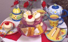 a table topped with cakes and cupcakes on top of plates next to flowers