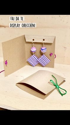 a pair of earrings is sitting on top of a table next to an open card