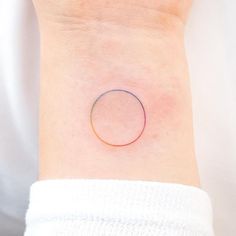 a woman's wrist with a small circle tattoo on the left side of her arm