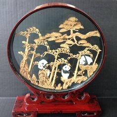 there is a red and black plate with pandas in it on a stand next to a wall