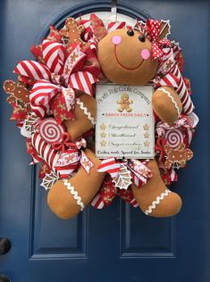 a christmas wreath with a gingerbread man holding a sign on it's front door