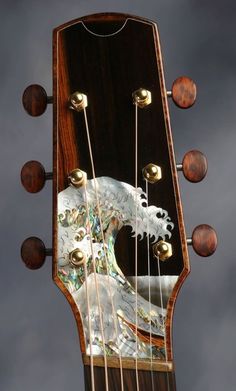 a close up of an acoustic guitar's frets and strings with a painting on it