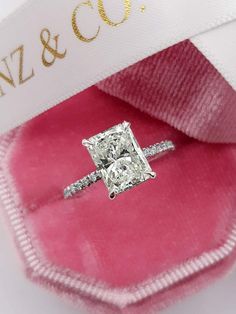 a diamond ring sitting on top of a pink velvet bag with the name n z & co written on it