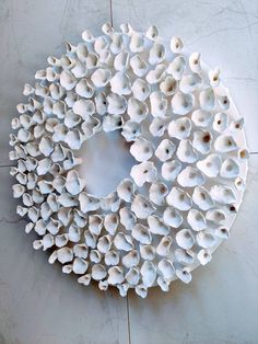 an arrangement of white ceramic objects on a tile floor in a circle shape, with one section cut out and the other half closed