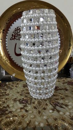 a white vase sitting on top of a table next to a gold plate and bowl