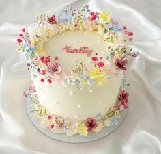 a white cake decorated with flowers and the word happy on it's frosting