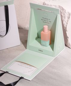 an open box containing a bottle of perfume next to a card with a message inside