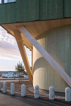 an unusual structure is on the side of a building by the beach with cars parked nearby