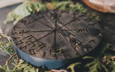 a wooden compass sitting on top of a table next to pine needles and other items