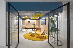 an office with chairs, tables and yellow rugs on the floor in front of glass walls