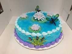 there is a blue cake with flowers and dragonflies on it