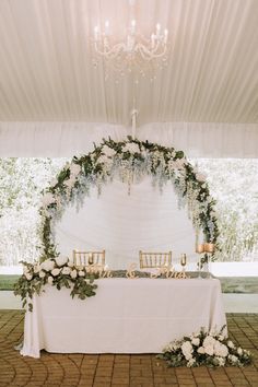 a table with white flowers and greenery is set up for an outdoor wedding reception