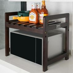 a microwave sitting on top of a wooden shelf next to a counter with bottles and pans