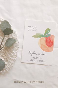 the wedding stationery has peaches on it and is next to some eucalyptus leaves