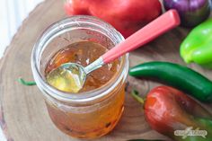 a jar filled with liquid sitting on top of a wooden cutting board next to vegetables