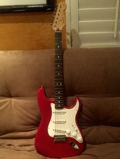 a red guitar sitting on top of a couch