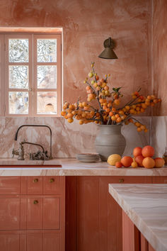 a vase filled with oranges sitting on top of a counter next to a sink