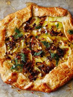 a pizza topped with lots of toppings on top of a piece of parchment paper