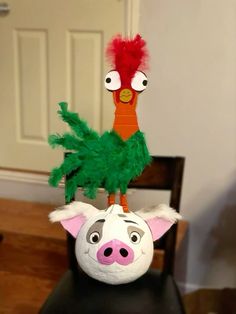 a stuffed animal head sitting on top of a wooden chair next to a fake carrot