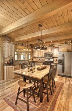 a kitchen and dining room with wood flooring in the middle, along with an island table surrounded by chairs